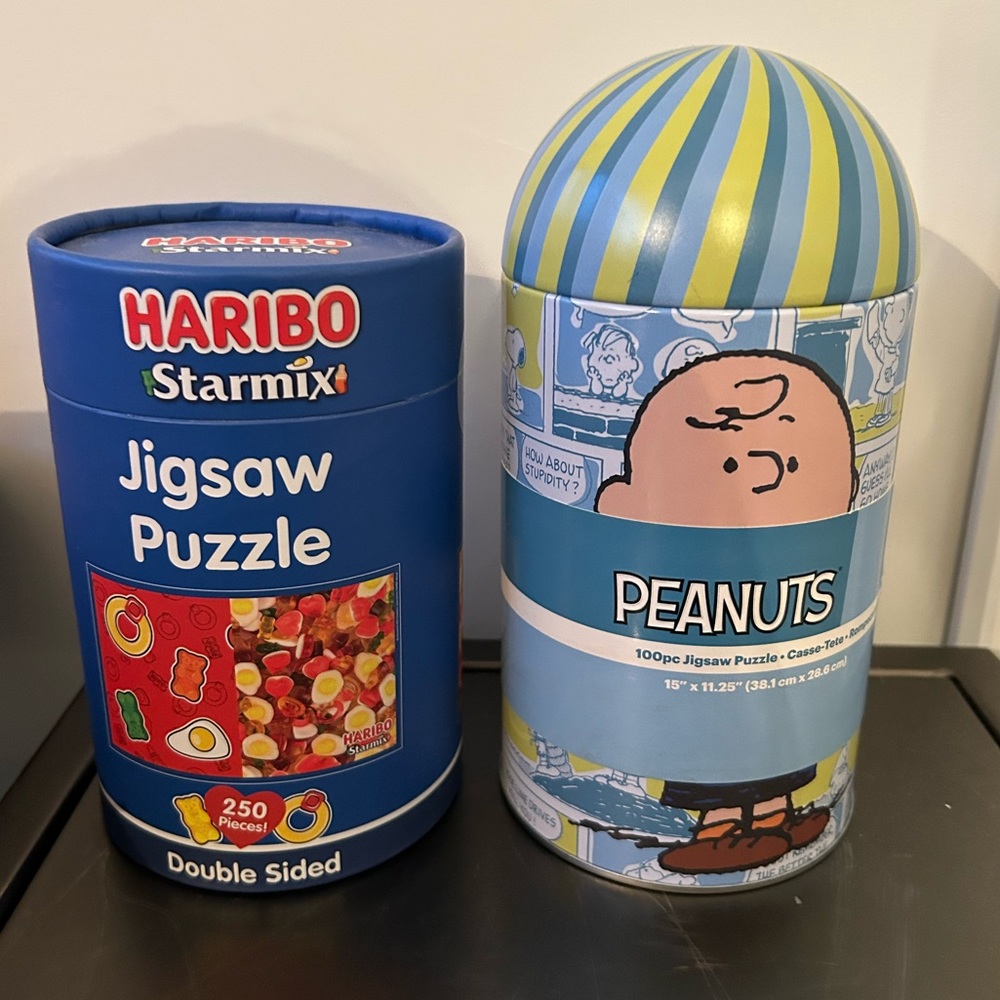 Two sets of unopened jigsaw puzzles, Peanuts and Haribo gummies